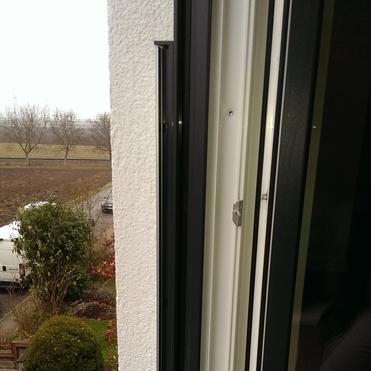 Blick aus einem geöffneten Fenster auf einen Garten und Parkplatz mit Bäumen und einem weißen Lieferwagen.