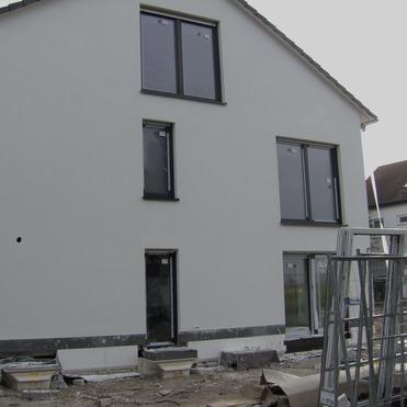 Bauhaus mit weißer Fassade, großen Fenstern und Baustellenmaterialien im Vordergrund.