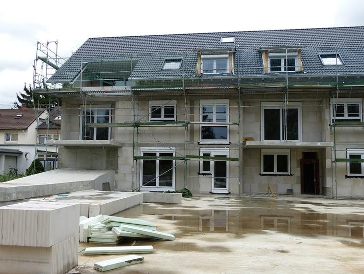 Bauhaus mit Gerüst und offenen Fenstern; Bauarbeiten und Materialien liegen im Vordergrund.