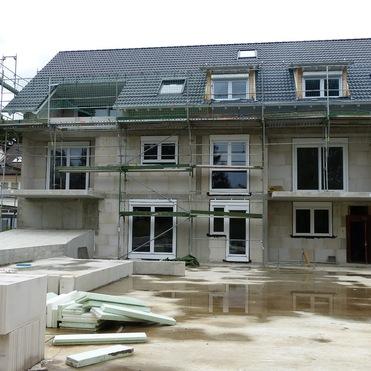 Bauhaus mit Gerüst und offenen Fenstern; Bauarbeiten und Materialien liegen im Vordergrund.